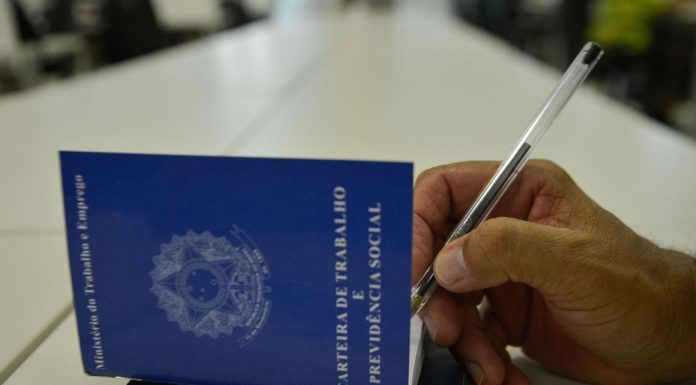 homem assina com caneta a carteira de trabalho