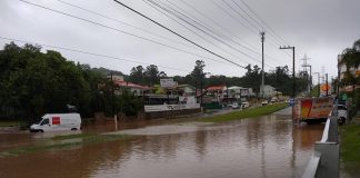 grande área alagada bem no meio da avenida das torres; carros ilhados ao fundo e uma van tentando passar pela água