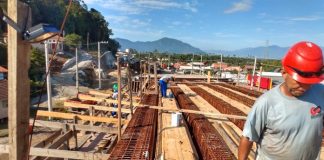 operário usando capacete anda sobre armação de ferro e madeira do elevado