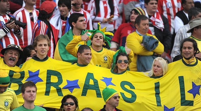 torcedores do brasil usando uma camisa larga que envolve todos, o da esquerda é o "gaúcho da copa"