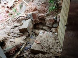 Muro desaba e mata menina de 12 anos soterrada na Fazenda Santo Antônio lama e pedras revirados ao lado da porta de uma casa, parcialmente destruída
