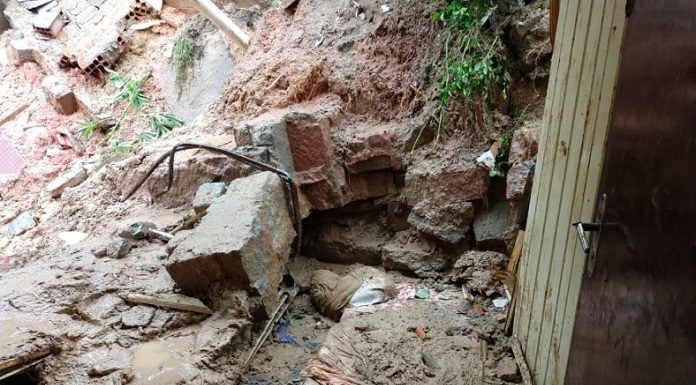 lama e pedras revirados ao lado da porta de uma casa, parcialmente destruída