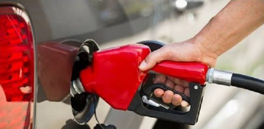 pessoa segura bico de bomba de gasolina abastecendo um carro