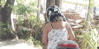 duas mulheres em uma moto paradas ao lado da calçada; placa e tatuagens estão censuradas