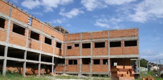 prédio de dois andares em forma de L em construção, com tijolos à mostra