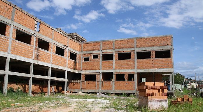 prédio de dois andares em forma de L em construção, com tijolos à mostra