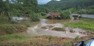 área rural alagada com o carro da defesa civil estacionado na frente