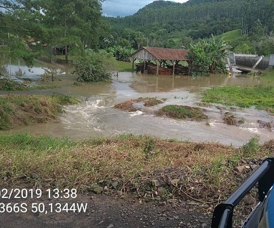 área rural alagada com o carro da defesa civil estacionado na frente