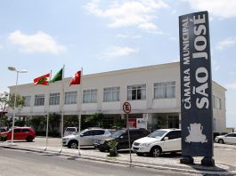 foto externa do prédio camara de vereadores de são Joosé com um placa vertical na frente e carros estacionados