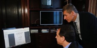 governador mexe no computador e secretario ao lado olhando para a tela