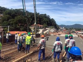 trabalhadores com capacetes em cima da estrutura de ferro de elevado para ser concretada