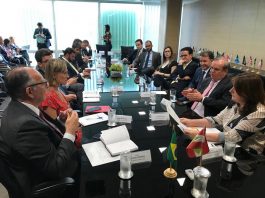 diversas pessoas reunidas e conversando em volta de uma grande mesa preta