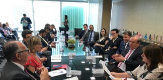 diversas pessoas reunidas e conversando em volta de uma grande mesa preta