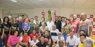 adeliana e o vice prefeito posam com grande grupo de atletas (homens e mulheres) no gabinete da prefeitura