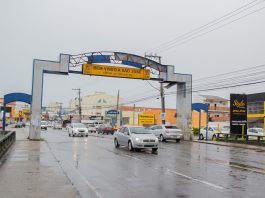 pórtico da avenida leoberto leal com placas de trânsito e carros passando em baixo em dia de chuva