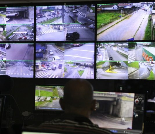Com mais estragos registrados, cidades ficam alertas às chuvas homem olhando um painel com diversas telas de cameras de ruas na central de videomonitoramento