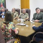 integrantes da pm e do tjsc conversam em uma mesa com o secretario nacional, que está de costas na ponta