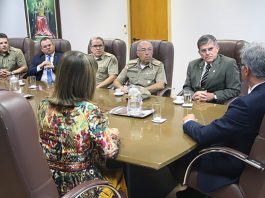 integrantes da pm e do tjsc conversam em uma mesa com o secretario nacional, que está de costas na ponta