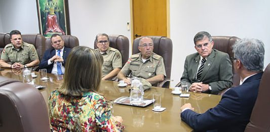 Projetos inovadores do Judiciário catarinense na segurança serão replicados no Brasil integrantes da pm e do tjsc conversam em uma mesa com o secretario nacional, que está de costas na ponta