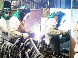 Taxa de desemprego volta a crescer depois de duas quedas consecutivas operários de solda trabalhando e outros olhando para a câmera