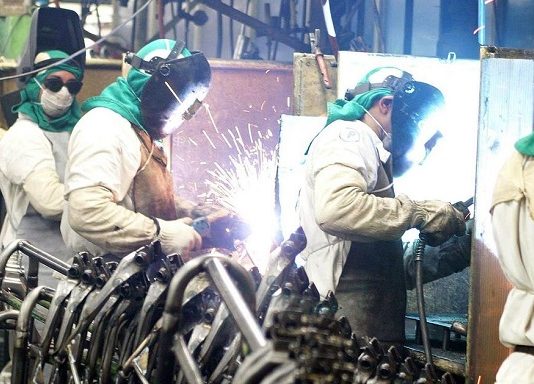 operários de solda trabalhando e outros olhando para a câmera