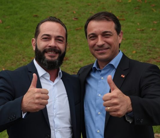 comin e moisés abraçados sorriem e fazem sinal de positivo para a câmera