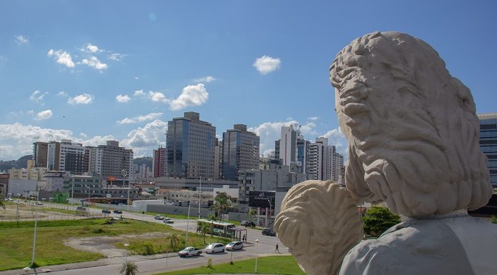 foto na altura da cabeça da estátua com a cidade de fundo