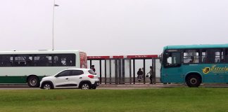 um ônibus da estrela atrás de um ônibus da jotur na beira-mar de são josé e um carro passando na frente
