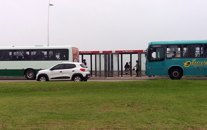 um ônibus da estrela atrás de um ônibus da jotur na beira-mar de são josé e um carro passando na frente