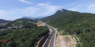 obra do contorno viário vista do céu: duas pistas novas sem pintura cortando região de mata e morros