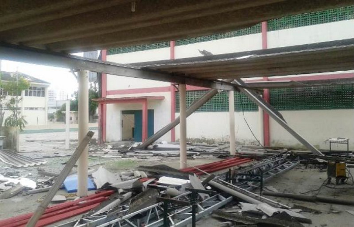 pátio da escola com muitas telhas e peças quebradas, ao lado do ginásio