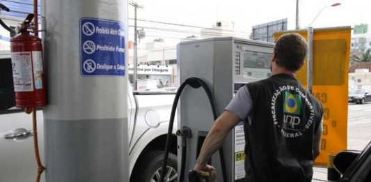 Preço da gasolina sobe pela 4ª semana e acumula alta de 3,5% em um mês agente da anp usando colete retira gasolina de uma bomba em posto