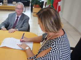 Estado faz novo pedido de cessão de área para São José adeliana sentada na ponta da mesa assina um documento observada pelo delegado geral