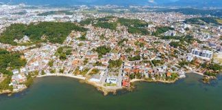 imagem aérea da cidade mostrando grande concentração de prédios e construções, com a orla marítima do centro histórico ao centro