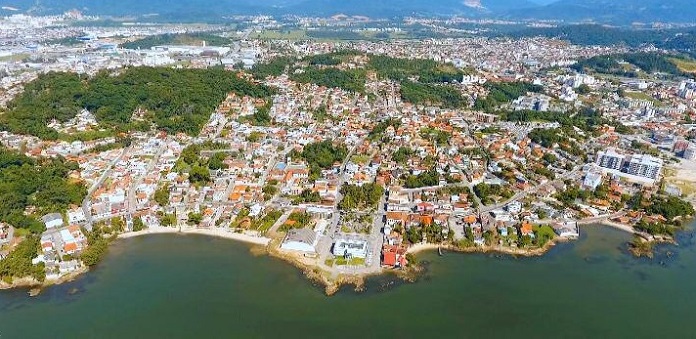 imagem aérea da cidade mostrando grande concentração de prédios e construções, com a orla marítima do centro histórico ao centro