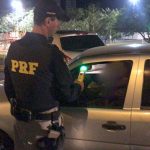 Policial rodoviário fazendo o teste de bafômetro em motorista