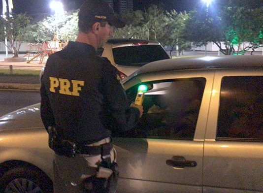 Policial rodoviário fazendo o teste de bafômetro em motorista
