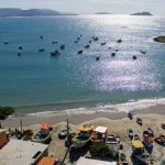 vista aérea da praia da armação com barcos ancorados e quiosques na praia