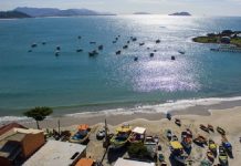 vista aérea da praia da armação com barcos ancorados e quiosques na praia