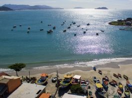 vista aérea da praia da armação com barcos ancorados e quiosques na praia