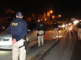 diversos agentes da prf na estrada com carros passando pela blitz