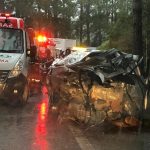 carro destruído no acostamento com ambulâncias ao lado
