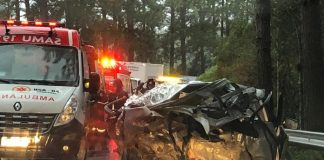 carro destruído no acostamento com ambulâncias ao lado