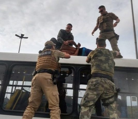 PM prende homem “alterado” em cima de ônibus no elevado do CIC dois policiais seguram o homem em cima do ônibus e outros dois embaixo olhando