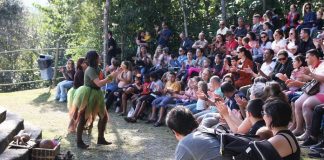 mulher fantasiada se apresenta para plateia cheia em pequeno anfiteatro ao ar livre