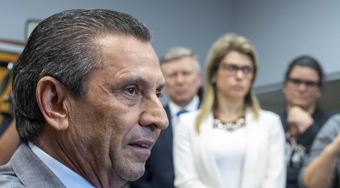 close em julio garcia com pessoas em pé ao fundo