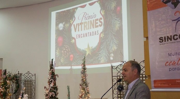 lédio em uma pequena tribuna falando com palco ao lado com decorações de natal