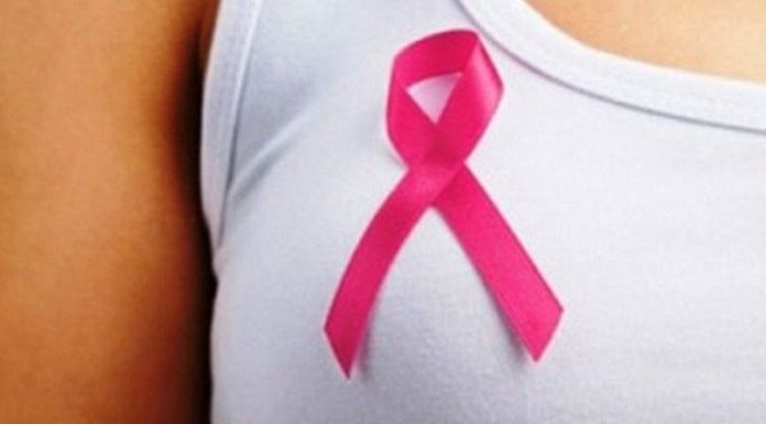 laço símbolo da campanha outubro rosa sobre o seio de uma mulher usando blusa