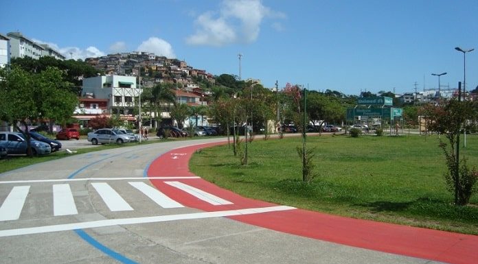pista de corrida sem ninguém no parque de coqueiros e construções ao fundo