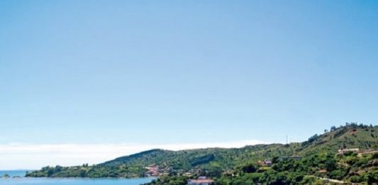 Deputados votam nesta terça proibição de pedágios ambientais em SC vista superior da praia calma com alguns barcos na água e morros com muita vegetação em volta
